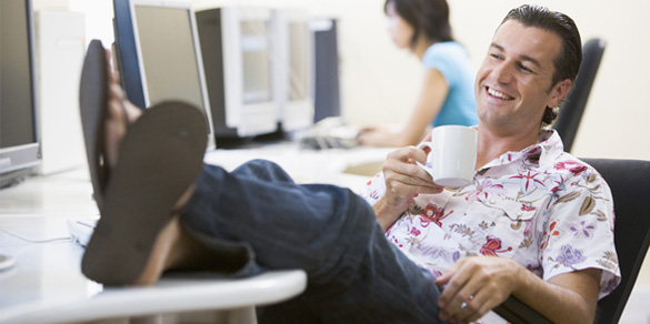 Person sitting at a desk with their feet up on it, reclining.